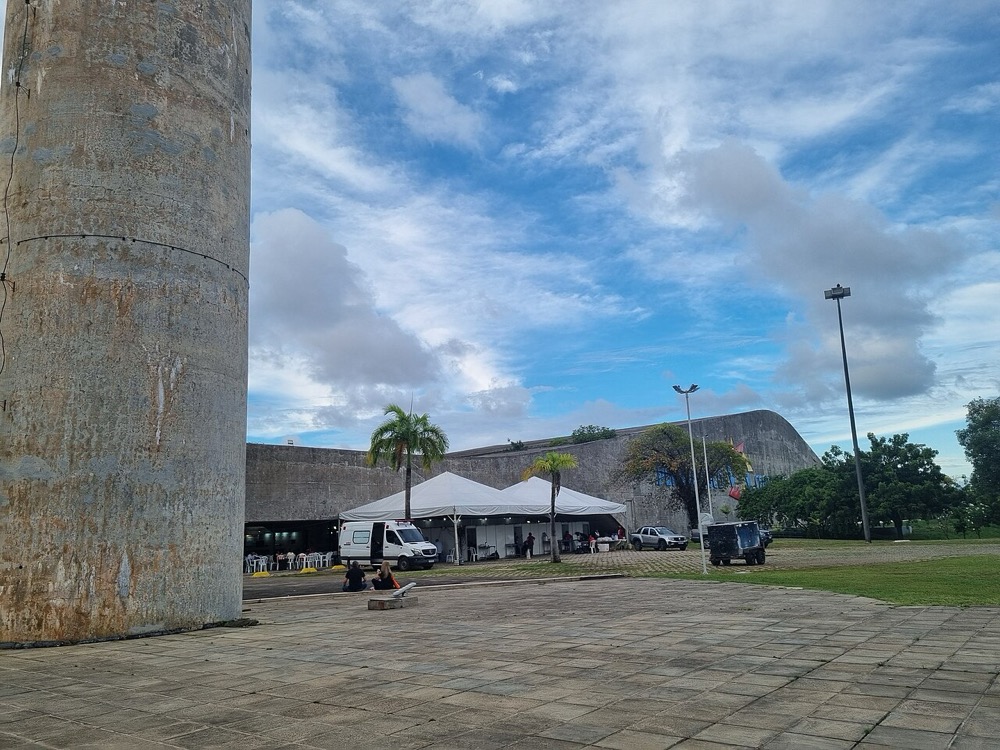 pavilhão de teto curvo visto da esplanada externa, com tendas na frente